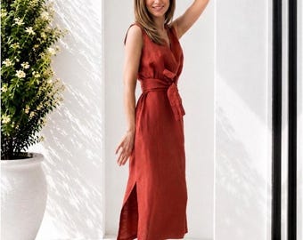 May include: A sleeveless midi dress in a deep rust-red color featuring a V-neckline, a matching fabric tie belt at the waist, and a side slit on the skirt. The dress is constructed with a visible textured fabric and falls to mid-calf length.