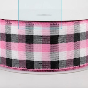 Puede incluir: Un rollo de cinta de cuadros de búfalo rosa, negro y blanco. La cinta está en una bobina de cartón blanco. La cinta es una cinta ancha y decorativa, perfecta para manualidades, envolver regalos o decoración de temporada.