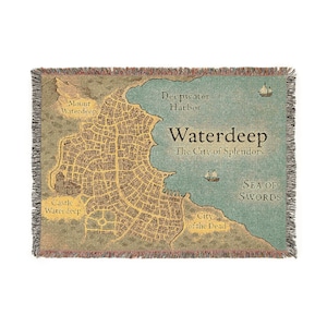 May include: Woven throw blanket depicting a map of Waterdeep, The City of Splendors, with the Sea of Swords and Deepwater Harbor. The map includes Castle Waterdeep, Mount Waterdeep, and City of the Dead. The blanket has a fringed edge.