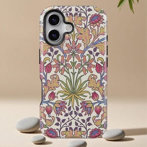 May include: A phone case with a floral pattern in pink, orange, yellow, and purple on a cream background. The design features stylized flowers and leaves. The case has a black camera lens cutout and a black border.
