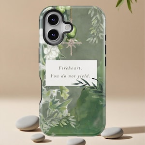 May include: A green and white phone case with a floral design and the text "Fireheart. You do not yield." The case features a gold star-shaped charm and a camera cutout. The background is a watercolor-style wash of green.