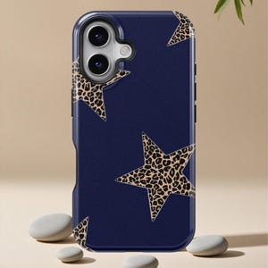 May include: A navy blue phone case with a pattern of leopard print stars. The case has a protective design with a camera cutout and is made of a durable material. The case is designed to fit a smartphone.