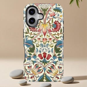 May include: A phone case featuring a floral pattern in cream, red, pink, yellow, and blue. The design includes stylized flowers and leaves, creating a vintage aesthetic. The case has a black camera lens surround and is set against a neutral background.