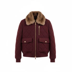 May include: A burgundy quilted bomber jacket with a faux fur collar. The jacket features two front pockets with gold button closures and a gold zipper. The jacket's measurements are not visible in the image.
