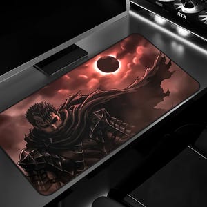 Puede incluir: Alfombrilla de ratón rectangular con una ilustración dramática de un personaje con capa contra un cielo rojo con un sol oscuro. La obra de arte es detallada y la paleta de colores es principalmente roja, negra y marrón. La alfombrilla está sobre un escritorio.