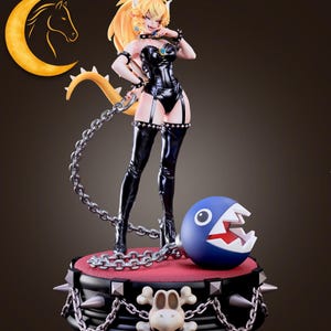 May include: A figurine of a character with blonde hair, a crown, and a black outfit, holding a chain. The figurine stands on a platform with a red top, surrounded by a chain and spikes, with a blue ball with teeth.