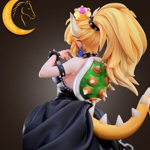 May include: A figurine of a character with blonde hair, a crown, and a black dress. The character has a green shell on their back and a yellow tail. The figurine is detailed and appears to be from a video game.