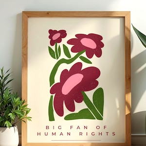 Könnte beinhalten: Ein gerahmter Wandkunstdruck mit cremefarbenem Hintergrund und zwei stilisierten kastanienbraunen und rosafarbenen Blumen auf grünen Stielen. Der Text "BIG FAN OF HUMAN RIGHTS" steht in kastanienbraunen Großbuchstaben unten, unterstrichen von einer Linie.