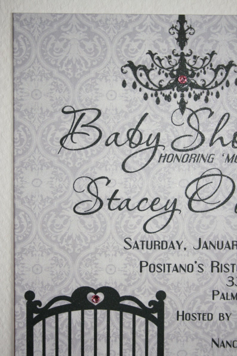Peut inclure: Une invitation &agrave; une baby shower avec un fond &agrave; motif de damas gris. L'invitation pr&eacute;sente un texte en noir qui dit "Baby Shower" et "Stacey O". Un lustre noir et un graphique de berceau sont &eacute;galement inclus, chacun avec un bijou rose.