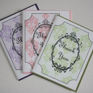 May include: Three thank you cards with a damask pattern and a black ornate frame with the text "Thank You" in cursive.
