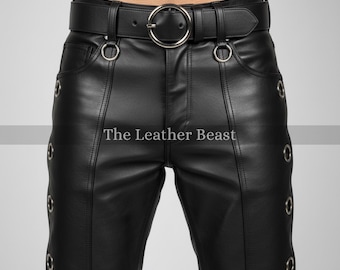 May include: Black leather pants with a matching belt featuring a large silver buckle. The pants have silver eyelets along the side seams and the text "The Leather Beast" is printed on the pants.