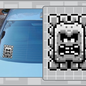 May include: A gray and white pixelated image of a monster with a large mouth and teeth. The monster is in a square frame with a gray background.