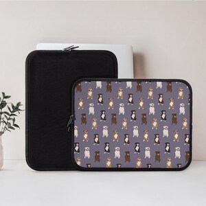 May include: A black laptop sleeve and a smaller tablet sleeve with a repeating pattern of various dog breeds on a gray background. The laptop sleeve is solid black, and the tablet sleeve has a black zipper.