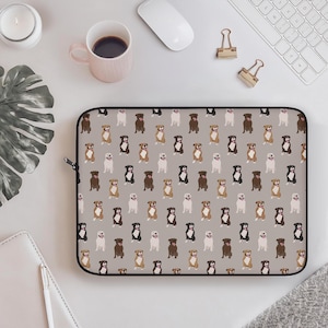 May include: A gray laptop sleeve featuring a repeating pattern of various dog breeds in brown, black, and white. The sleeve has a black zipper and is surrounded by office supplies, including a coffee cup and a computer mouse.