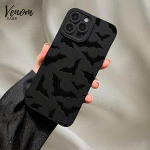 May include: A matte black smartphone case featuring a repeating embossed bat pattern across the entire surface. The case includes a raised camera module cutout with three circular lens openings and a small circular flash aperture in the top corner.