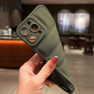 Pode incluir: Capa de telefone verde-oliva com design acolchoado. A capa tem uma se&ccedil;&atilde;o elevada para a c&acirc;mera com o texto "PRO Camera". A marca "Venom Case" &eacute; vis&iacute;vel no canto superior esquerdo.