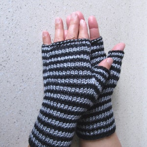 May include: A pair of black and silver striped fingerless gloves. The gloves are knitted and have a ribbed texture.