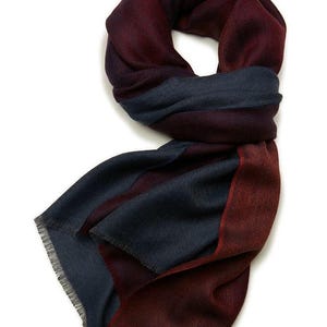 Puede incluir: Bufanda plegada en tonos burdeos y azul marino. La bufanda tiene un borde con flecos y un patrón de espiga. El texto "(4) 熱血燃燒" está en la esquina superior izquierda. Accesorio de moda.