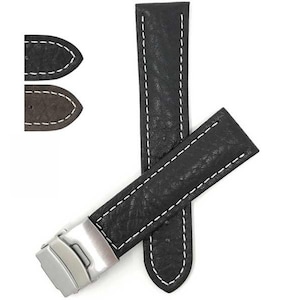 May include: Black leather watch strap with white stitching and a silver clasp. The strap has a textured surface. Additional end pieces in black and brown are also shown.