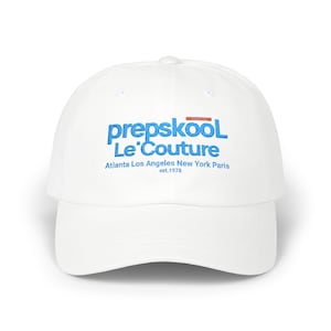 May include: A white baseball cap with a curved brim. The cap features the text "prepskool Le' Couture" in blue, with additional text below indicating locations and the year 1978. The cap is a classic style.