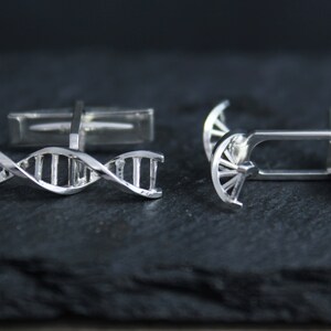 Pu&ograve; includere: Un paio di gemelli d'argento con un design a doppia elica di DNA. I gemelli sono realizzati in metallo lucido e hanno un aspetto classico ed elegante.