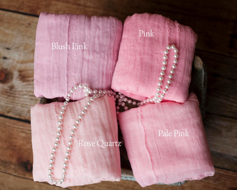 May include: Four squares of pink fabric, labeled "Blush Pink", "Pink", "Rose Quartz", and "Pale Pink". A strand of white pearls is draped over the fabric squares.