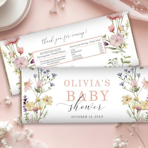 May include: Two white candy bar wrappers with floral designs and text. One wrapper reads "thank you for coming!" and includes nutrition facts. The other wrapper says "Olivia's Baby Shower" with the date.