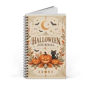 Könnte beinhalten: Ein spiralgebundenes Notizbuch mit cremefarbenem Einband und dem Text HALLOWEEN JOURNAL. Das Design zeigt eine Mondsichel, Sterne, Spinnweben, zwei Geister, Fledermäuse, eine schwarze Katze und drei orangefarbene Kürbisse umgeben von Herbstblättern.