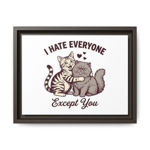 May include: A framed wall art print featuring a brown and white tabby cat hugging a fluffy grey cat. Above the cats, the text reads I HATE EVERYONE and below the cats, the text reads Except You. Three small hearts are positioned between the cats.