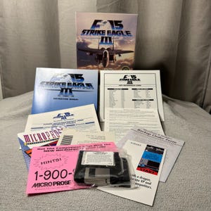 Könnte beinhalten: Eine Sammlung von Vintage-Computerspielmaterialien für "F-15 Strike Eagle III". Enthält die Spielbox, das Handbuch, die Schlüsselreferenzkarte und eine 3,5-Zoll-Diskette. Das Box-Art zeigt ein F-15-Kampfflugzeug. Verschiedene gedruckte Materialien sind enthalten.