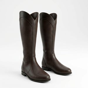 May include: A pair of tall, brown riding boots. The boots have a classic design with a V-shaped top and a smooth, leather-like appearance. The boots are knee-high and have a low heel.