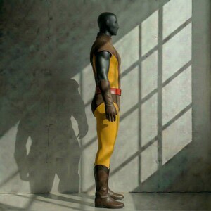 May include: A mannequin wearing a yellow and brown superhero costume with a red belt, brown gloves, and brown boots. The costume has a high collar and long sleeves. The mannequin is standing in front of a gray wall with sunlight shining through a window.