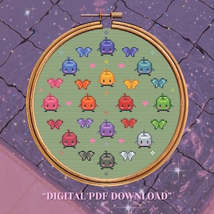 Puede incluir: Un patrón de punto de cruz en un bastidor de madera con fondo verde claro, que presenta personajes de frutas pixelados y coloridas mariposas dispuestos en una cuadrícula. El texto DIGITAL PDF DOWNLOAD aparece al pie de la imagen.