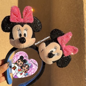 May include: Two Minnie Mouse ear headbands. One features a full Minnie Mouse face with a pink sequined bow. The other headband has a Minnie Mouse face with a pink sequined bow. The headband has a black band with blue accents. The image has the text "RnR Creations" and a heart-shaped image.