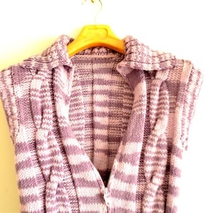 May include: A purple and white striped knitted vest with a collar and a V-neck. The vest is hanging on a wooden hanger.