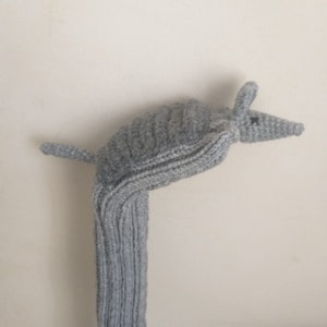 May include: A gray knitted golf club head cover shaped like an armadillo.