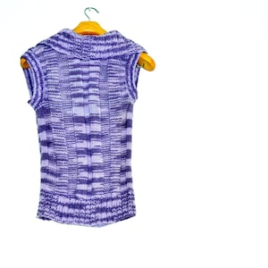 May include: A purple and white striped sleeveless sweater with a turtleneck collar hanging on a wooden hanger.