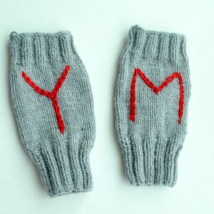 Könnte beinhalten: Ein Paar graue gestrickte Fingerhandschuhe mit roten gestickten Buchstaben, ein Handschuh hat ein "Y" und der andere ein "M" darauf.
