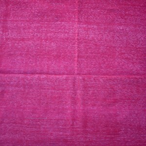 May include: A vibrant magenta rug with a textured surface. The rug features a dark blue zigzag border along the edges and a patterned border on one side. The rug is a home decor item.