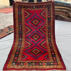 Pode incluir: Uma caneca de cerâmica branca com uma alça preta e o texto "But First, Coffee" em negrito preto. A caneca está sobre um fundo desfocado, sugerindo um ambiente acolhedor.