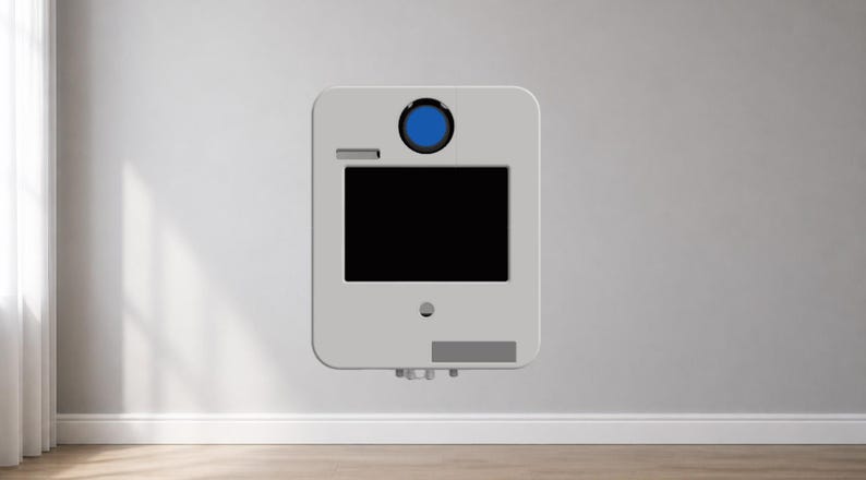 Puede incluir: Un dispositivo rectangular gris claro con esquinas redondeadas est&aacute; montado en una pared blanca. Cuenta con una pantalla negra, un elemento circular azul y una peque&ntilde;a secci&oacute;n rectangular. El dispositivo parece ser un producto tecnol&oacute;gico moderno.