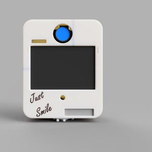 May include: A white photo booth with a black screen and the words "Just Smile" in cursive. It has a blue button and gold accents. The photo booth is rectangular with rounded corners.