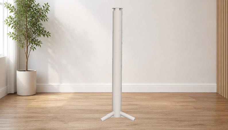 May include: A white, cylindrical stand with a three-legged base. The stand is made of metal and is designed to support a table or other object. The background includes a potted plant and a wooden floor. The stand's height is approximately 150 cm.