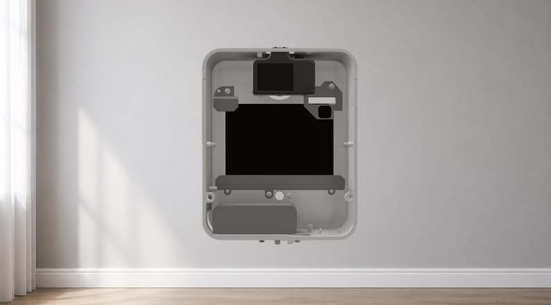 Puede incluir: Un dispositivo rectangular gris con una pantalla negra y varios componentes internos. El dispositivo est&aacute; montado en una pared blanca. Parece ser un panel de control para el hogar inteligente.