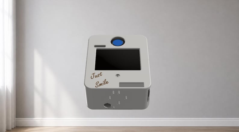 Puede incluir: Una cabina de fotos blanca y gris con una pantalla negra y un bot&oacute;n azul en la parte superior. Las palabras "Just Smile" est&aacute;n escritas en la parte delantera. La cabina tiene forma rectangular y flota en el aire.