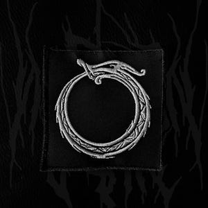 May include: Black square patch featuring a white embroidered Ouroboros design, a serpent eating its own tail. The patch is set against a dark, textured background with abstract patterns.