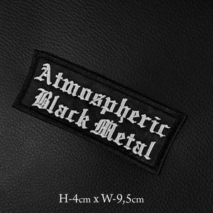 Può includere: Toppa rettangolare nera con testo ricamato bianco che recita "Atmospheric Black Metal". La toppa è alta 4 cm e larga 9,5 cm. Lo sfondo è una superficie nera strutturata.