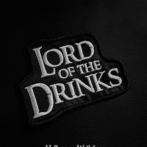 May include: Black embroidered patch with the text "LORD OF THE DRINKS" in white. The patch is 2.75 inches high and 3.74 inches wide. The patch is on a black background.