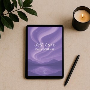 Könnte beinhalten: Ein digitales Tablet zeigt eine lila Landschaft mit dem Text "Self-Care Daily Journal". Ein schwarzer Stift liegt neben dem Tablet. Eine brennende Kerze in einem schwarzen Halter und eine grüne Pflanze befinden sich auf einer beigen Oberfläche.