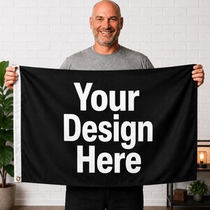 May include: A rectangular black flag featuring the white text "Your Design Here" printed in a bold, sans-serif font. The flag includes a white vertical header strip on the left side with two metal grommets for mounting purposes.